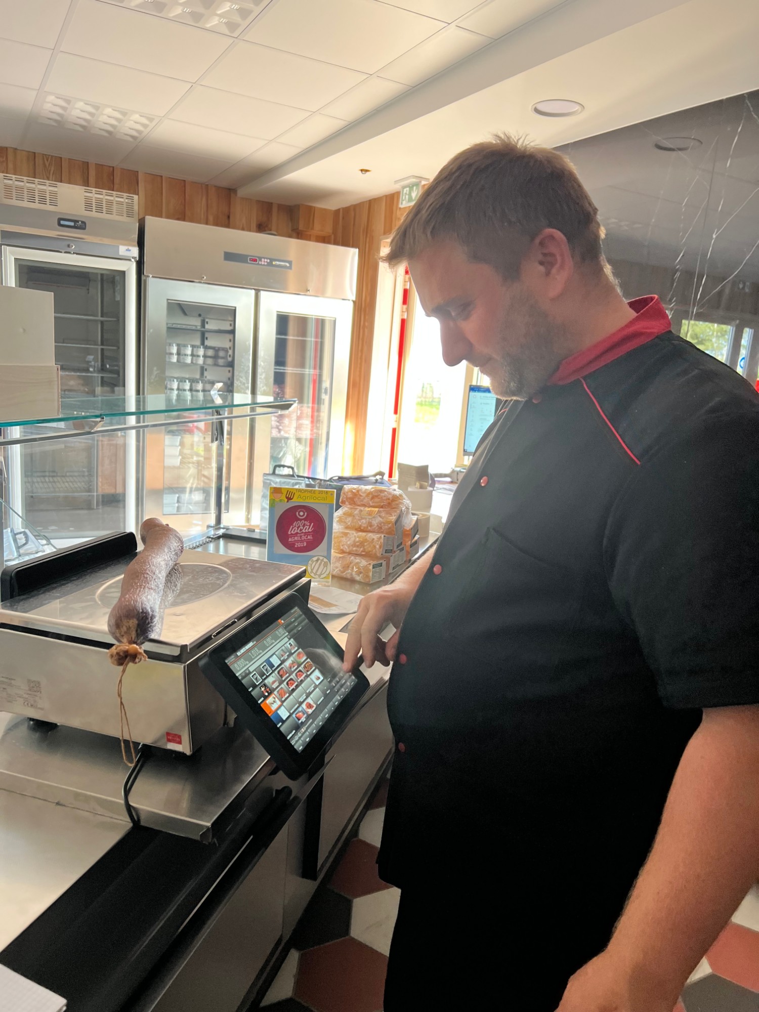 Boucher utilisant l'écran tactile ETPOS pour peser un produit